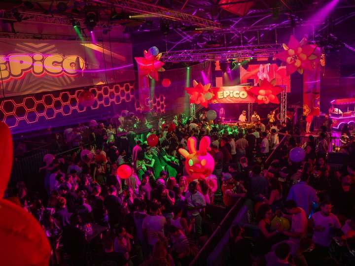 Carnival decor with giant flowers and an EPICO banner above a partying crowd