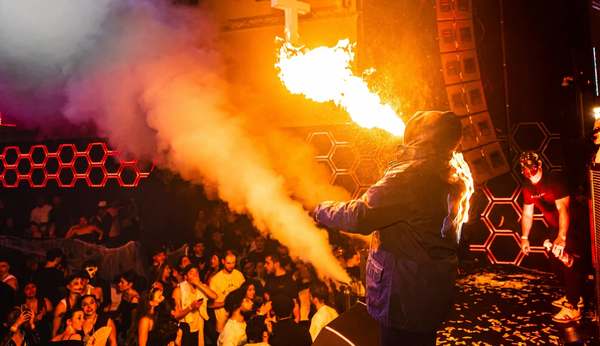 Fire breather on stage blowing a plume of flames over the crowd at an EPICO party in Brussels
