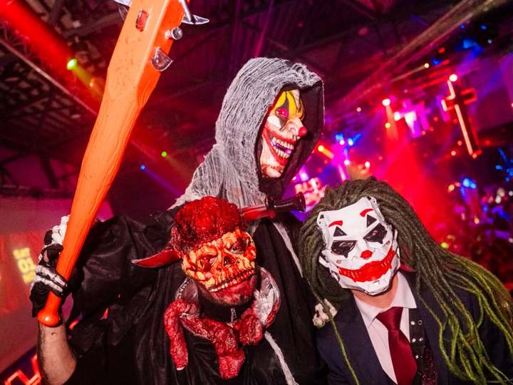 Tres fiesteros disfrazados para Halloween: parca con máscara de payaso, calavera ensangrentada y Joker, en la fiesta EPICO