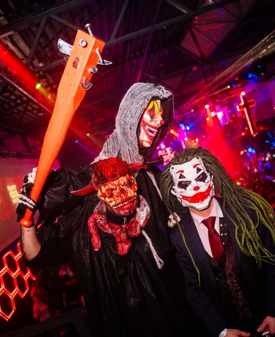 Three Halloween partygoers in costume — a clown-masked reaper, a bloody skull and the Joker — at the EPICO party