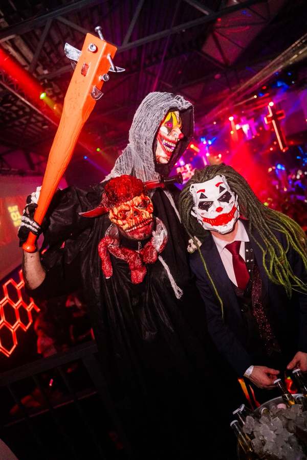 Three Halloween partygoers in costume — a clown-masked reaper, a bloody skull and the Joker — at the EPICO party