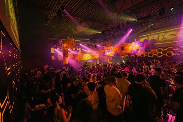 Purple and green light show over the crowd at a large EPICO Latin party