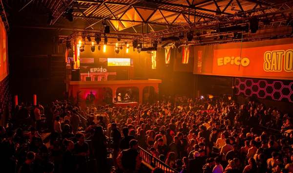 Packed hall bathed in orange light beneath EPICO banners, seen from the back of the room