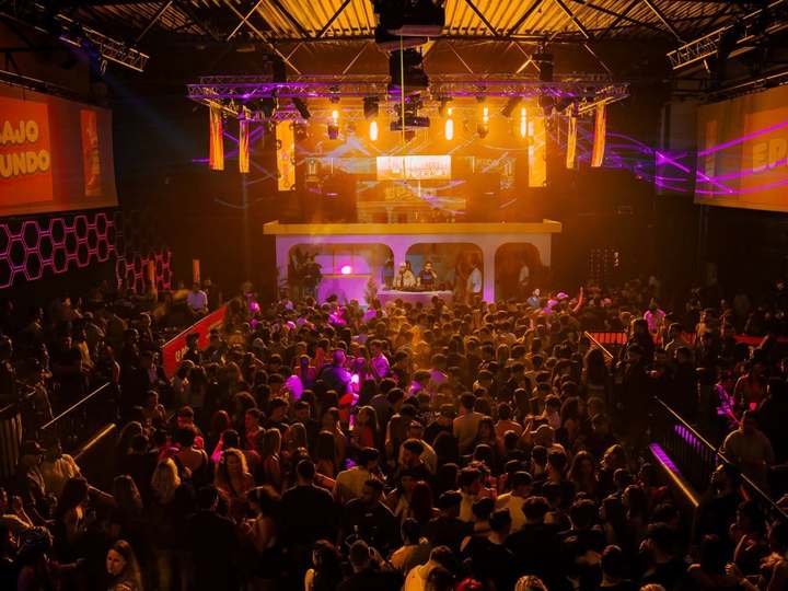 Público frente a la cabina del DJ iluminada, entre los carteles de Bajo Mundo y EPICO
