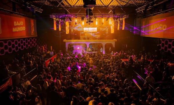 Crowd facing the lit-up DJ booth between the Bajo Mundo and EPICO banners