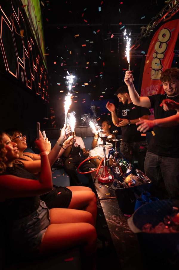 Bottle service with sparklers at a VIP table, under falling confetti and an EPICO flag
