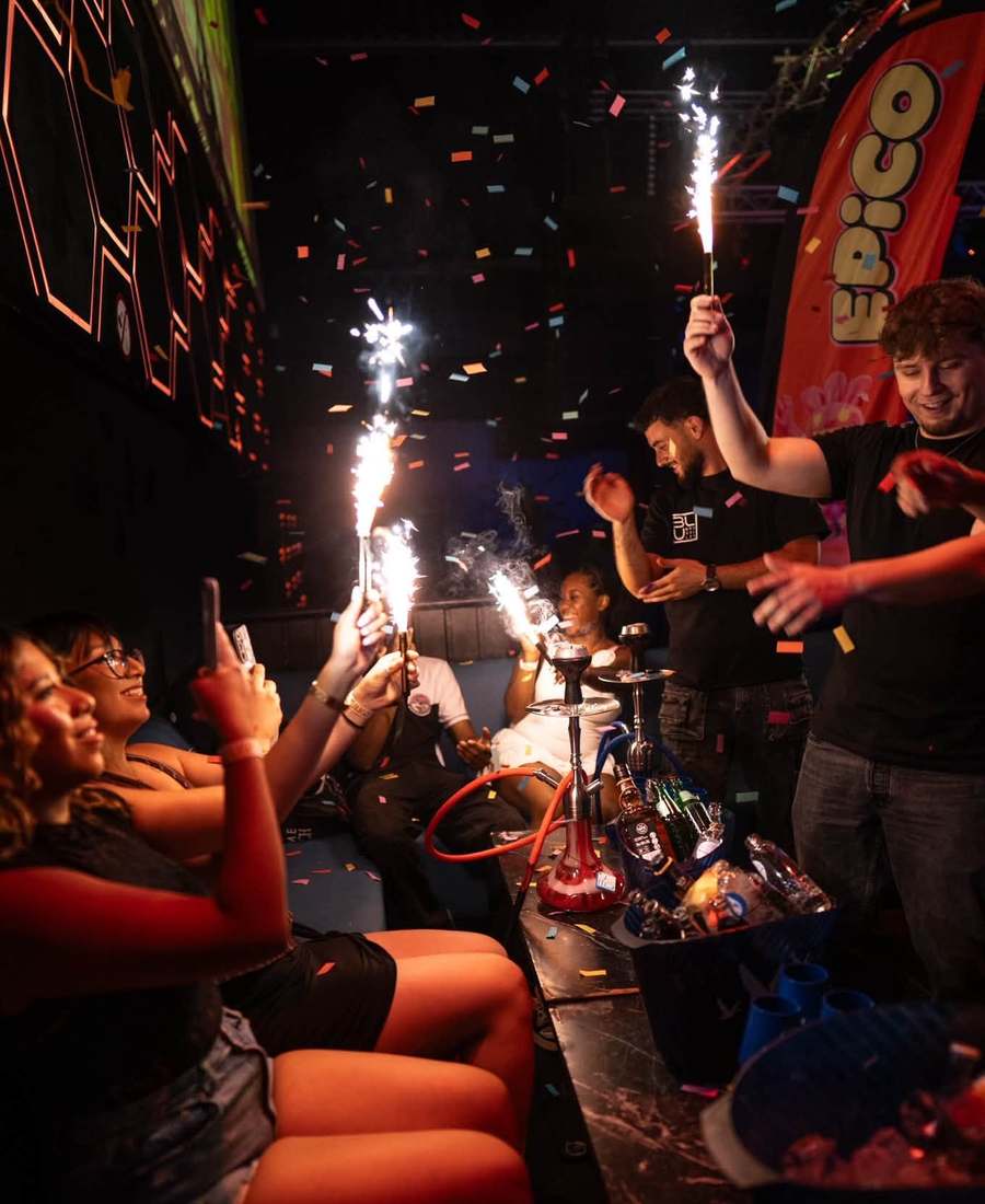 Bottle service with sparklers at a VIP table, under falling confetti and an EPICO flag